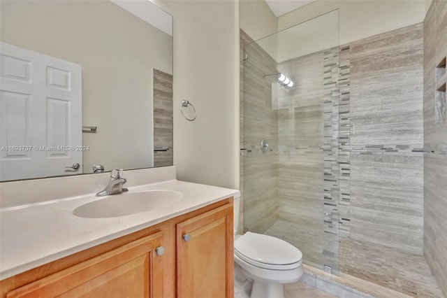 bathroom with a tile shower, vanity, toilet, and tile patterned floors