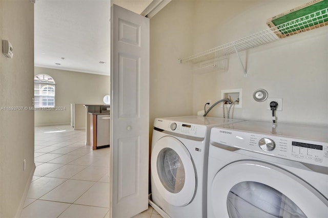 clothes washing area featuring washer and dryer, light tile patterned floors, and crown molding