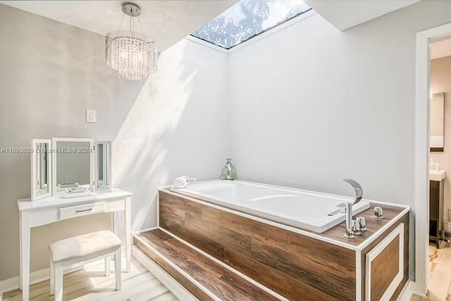 bathroom featuring a bathing tub, a skylight, a chandelier, wood-type flooring, and vanity