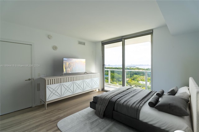 bedroom with hardwood / wood-style floors and expansive windows