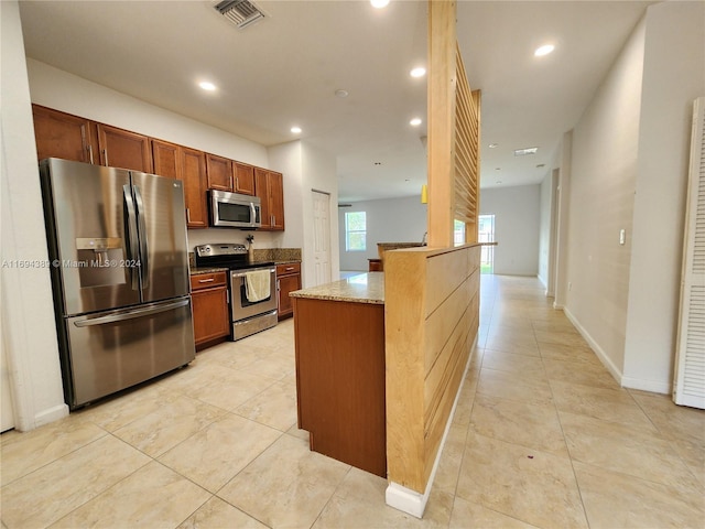 kitchen featuring stone counters, light tile patterned floors, kitchen peninsula, and appliances with stainless steel finishes