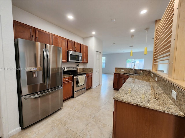 kitchen featuring pendant lighting, sink, appliances with stainless steel finishes, stone countertops, and kitchen peninsula