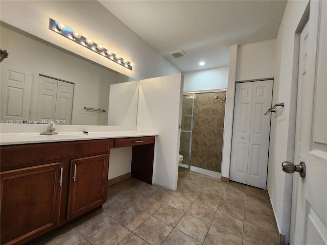 bathroom with an enclosed shower, vanity, toilet, and tile patterned flooring