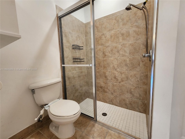 bathroom featuring tile patterned flooring, toilet, and an enclosed shower