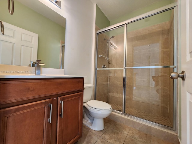 bathroom featuring tile patterned floors, a shower with door, vanity, and toilet