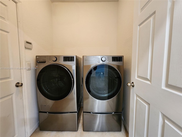 clothes washing area with light tile patterned flooring and washing machine and dryer