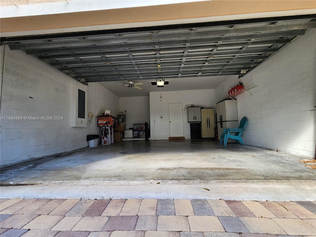 garage featuring ceiling fan, white fridge, electric panel, and a garage door opener