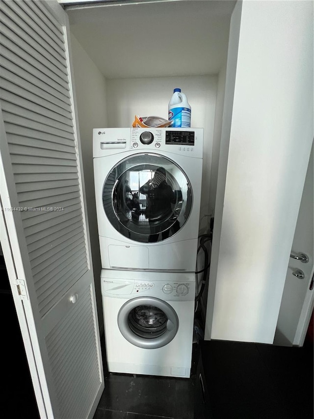 laundry area with stacked washer and dryer and dark tile patterned floors