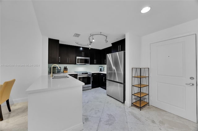 10 Aragon Ave Unit 810, Coral Gables, FL 33134 - kitchen featuring stainless steel appliances, light countertops, a peninsula, dark cabinetry, and rail lighting