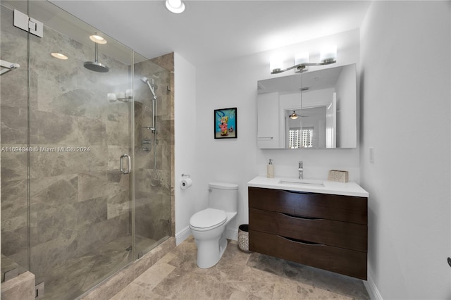 bathroom featuring vanity, a shower with door, toilet, and ceiling fan