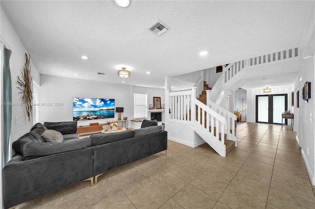 living room featuring french doors, light tile patterned floors, and a textured ceiling