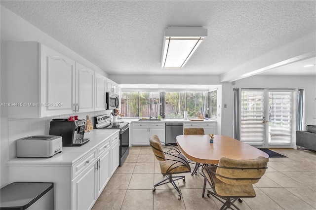 kitchen featuring white cabinetry, sink, stainless steel appliances, tasteful backsplash, and light tile patterned flooring