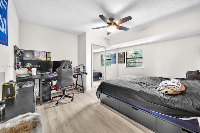 bedroom featuring ceiling fan, light wood-type flooring, a textured ceiling, and a closet