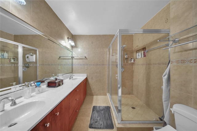 bathroom with walk in shower, tile patterned floors, toilet, vanity, and tile walls