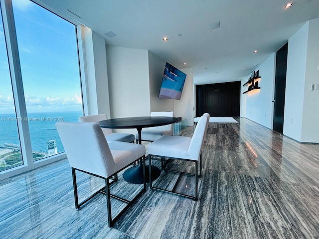 dining room with a wall of windows, a water view, and plenty of natural light