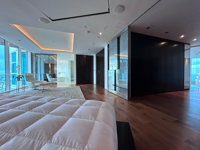 bedroom featuring a tray ceiling, expansive windows, and hardwood / wood-style flooring