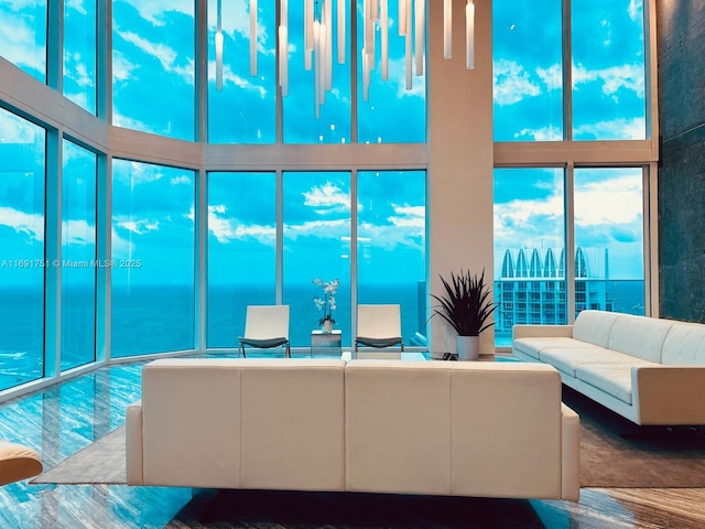 living room featuring a high ceiling, a healthy amount of sunlight, and a water view