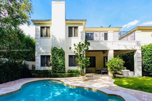 rear view of property with ceiling fan, a balcony, and a patio