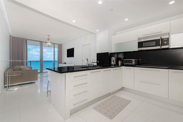 kitchen with white cabinets, expansive windows, sink, light tile patterned floors, and kitchen peninsula