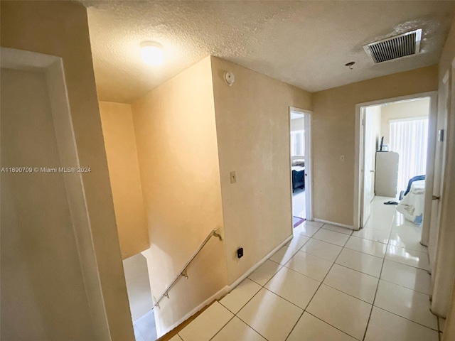 hallway with light tile patterned flooring and a textured ceiling