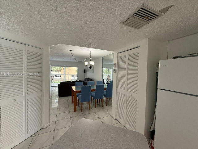 kitchen with a textured ceiling, white fridge, light tile patterned floors, and a notable chandelier