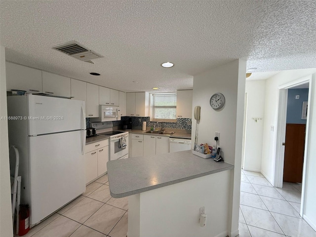 kitchen featuring sink, light tile patterned floors, a textured ceiling, white appliances, and white cabinets