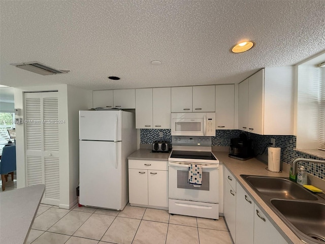 kitchen with white appliances, sink, a textured ceiling, tasteful backsplash, and white cabinetry