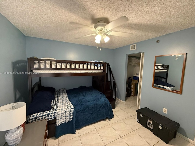 bedroom with ceiling fan, a closet, light tile patterned flooring, and a textured ceiling