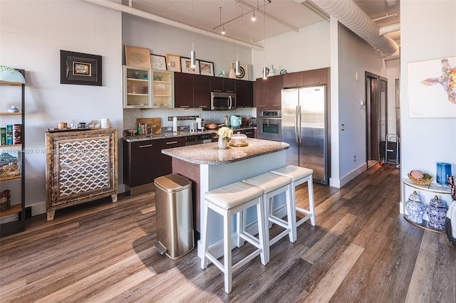 kitchen featuring a kitchen island, dark brown cabinetry, a towering ceiling, and stainless steel appliances