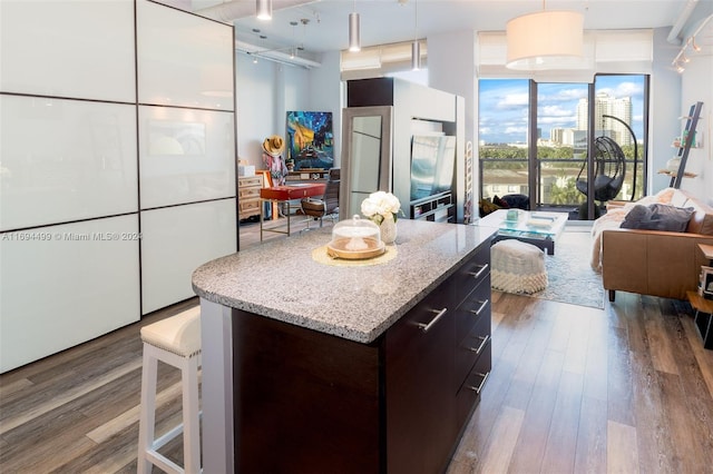 kitchen featuring hardwood / wood-style floors, pendant lighting, floor to ceiling windows, a kitchen island, and dark brown cabinetry