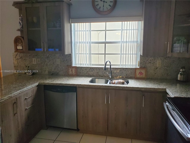 kitchen featuring decorative backsplash, dishwasher, light tile patterned floors, and sink