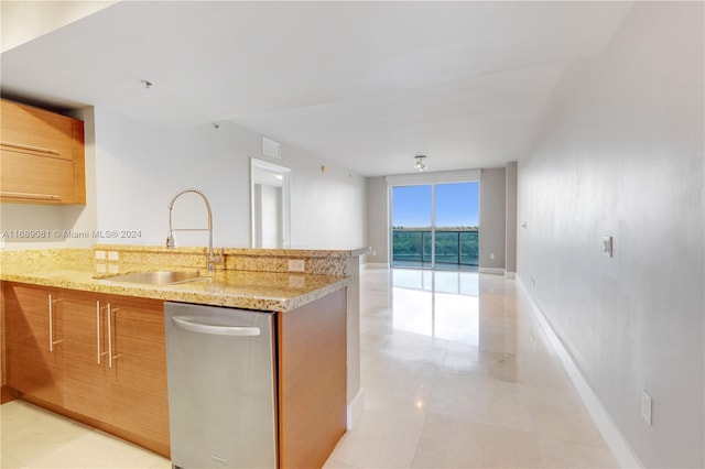 kitchen with stainless steel dishwasher, light stone counters, and sink