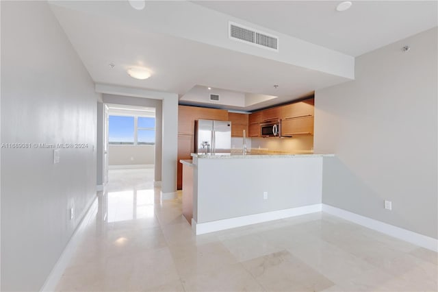 kitchen featuring kitchen peninsula, light stone countertops, and stainless steel appliances