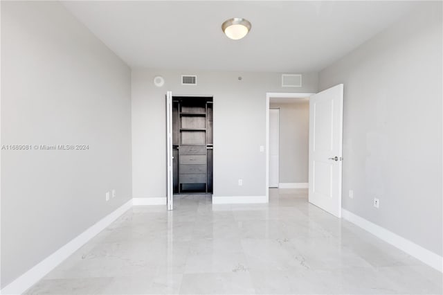 unfurnished bedroom featuring a walk in closet and a closet