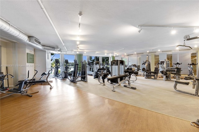 gym with a textured ceiling and light wood-type flooring