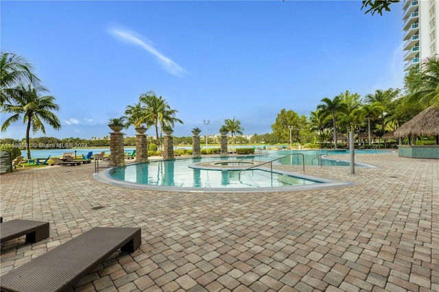 view of swimming pool featuring a water view, a hot tub, and a patio area