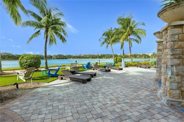 view of home's community with a lawn, a patio area, and a water view