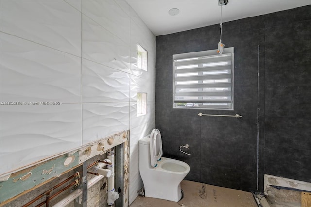 bathroom with toilet and tile walls