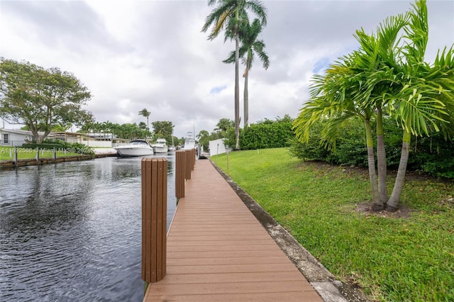 view of dock featuring a lawn and a water view