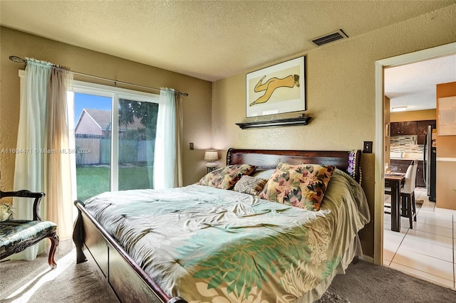 carpeted bedroom with access to exterior, a textured ceiling, and stainless steel refrigerator