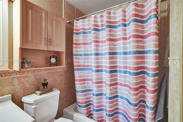 full bathroom with vanity, a textured ceiling, shower / bath combo with shower curtain, tile walls, and toilet