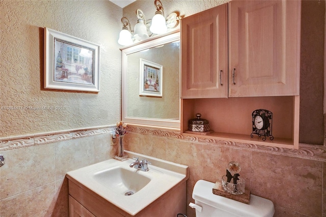 bathroom featuring vanity, toilet, and tile walls