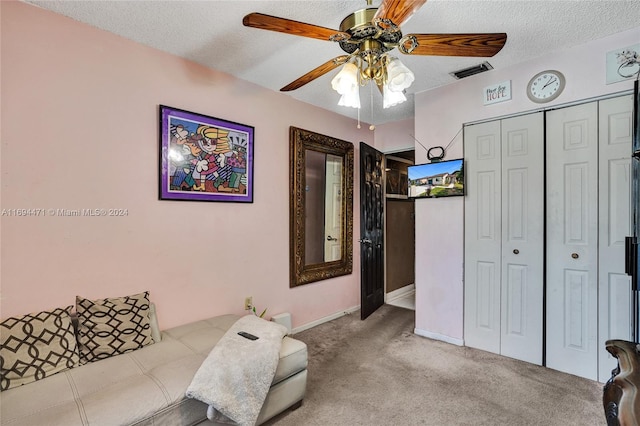 carpeted living room with a textured ceiling and ceiling fan