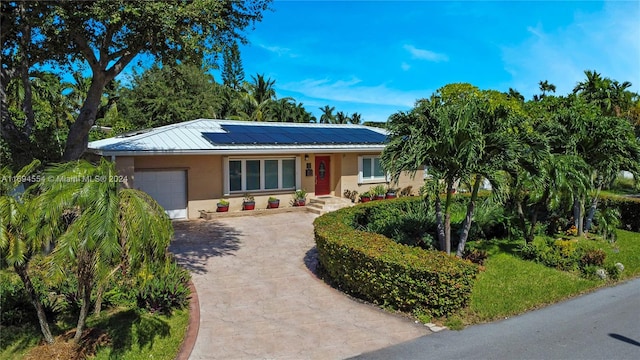 single story home with a garage and solar panels