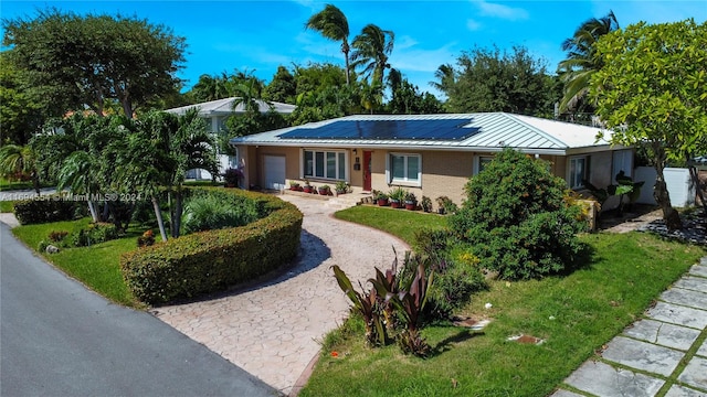 ranch-style house featuring solar panels, a garage, and a front lawn