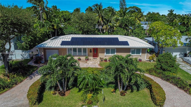 ranch-style home featuring solar panels and a garage