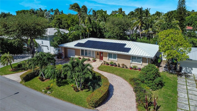 single story home featuring solar panels, a garage, and a front lawn