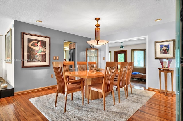 dining area featuring a textured ceiling, light wood-type flooring, and ceiling fan