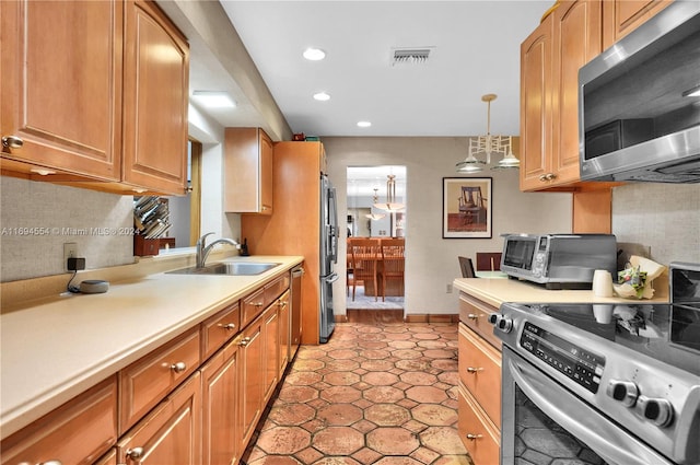 kitchen with sink, light tile patterned floors, stainless steel appliances, and hanging light fixtures