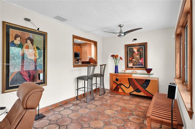 interior space with ceiling fan and a textured ceiling